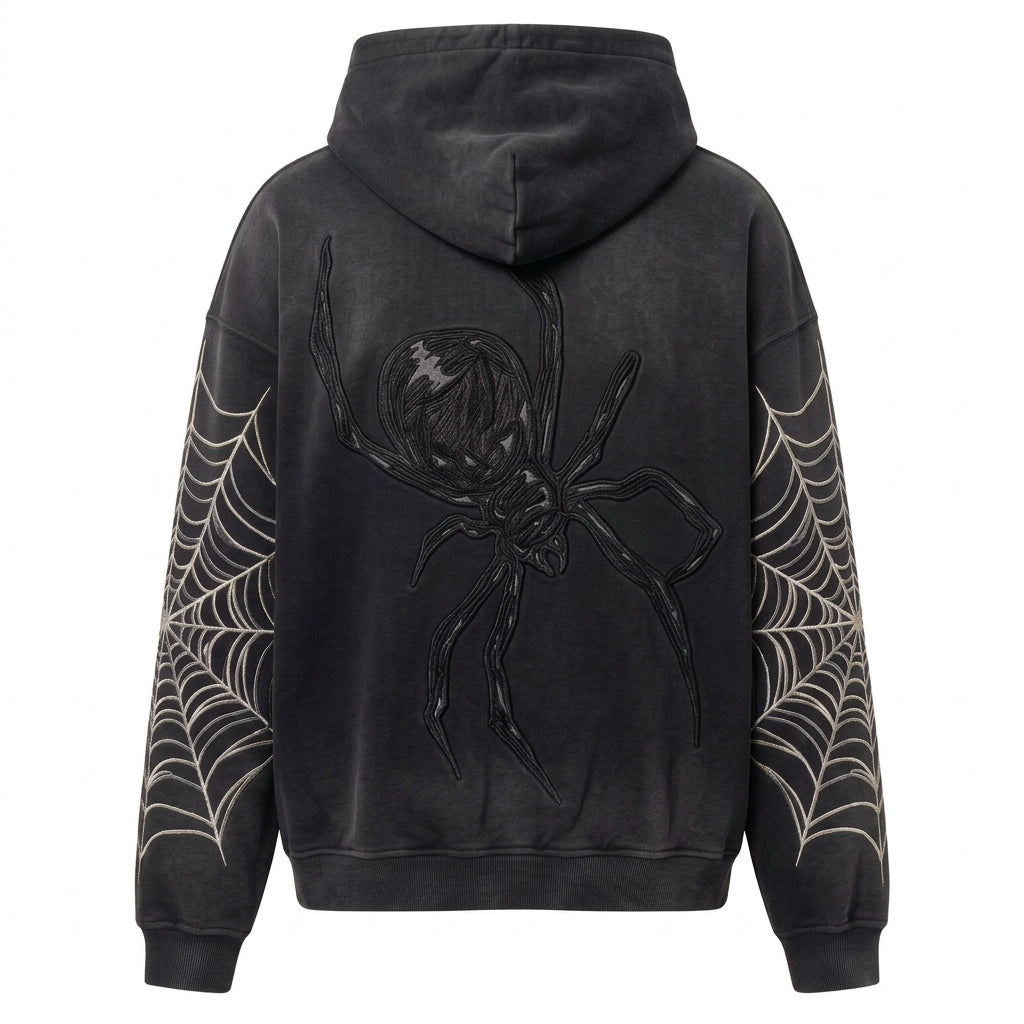 A black hooded sweatshirt shown from the back, featuring a large black spider graphic in the center and white spiderweb patterns printed down both sleeves, set against a light beige background.